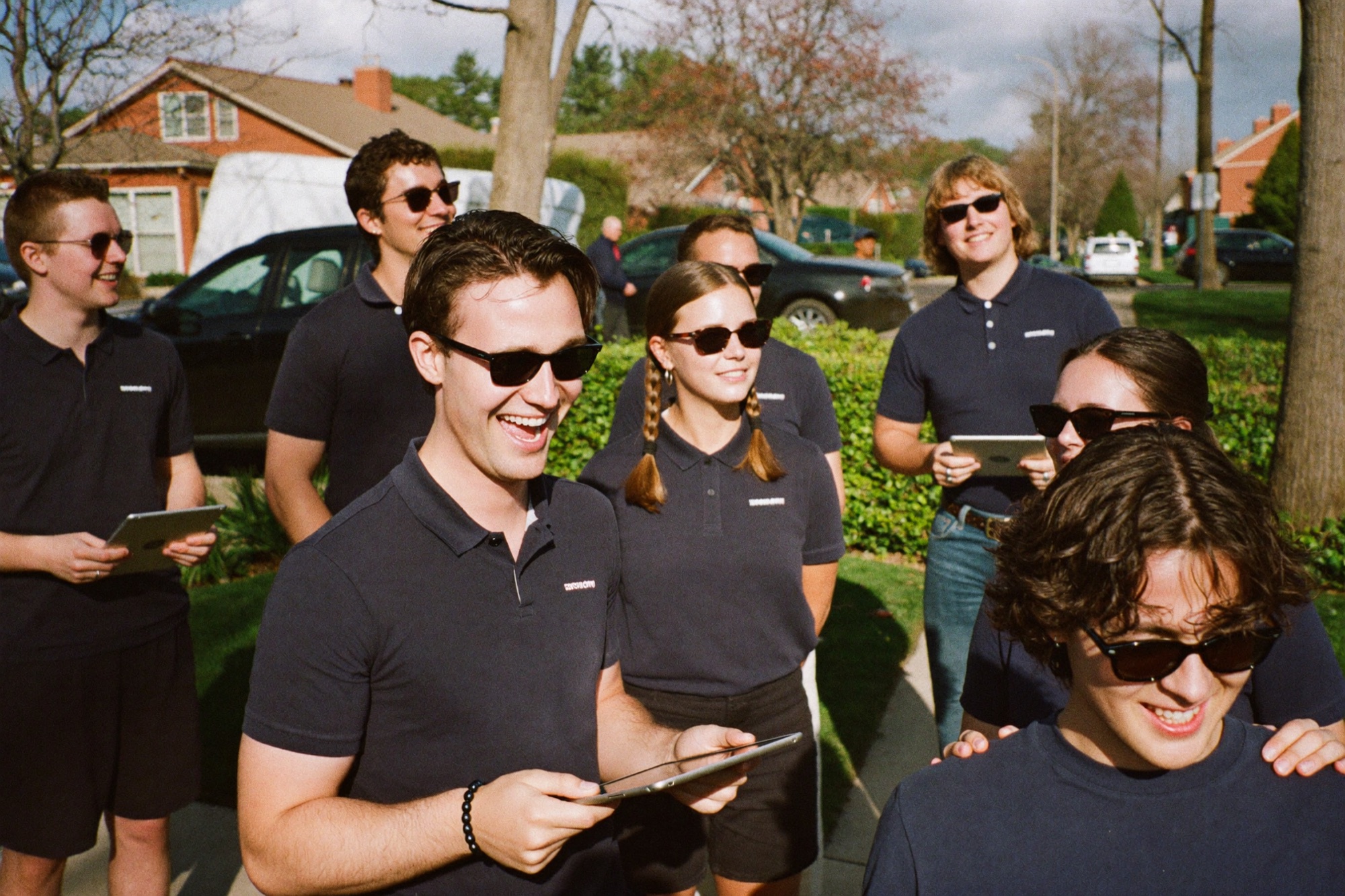 A door-to-door sales team laughing on a suburban sidewalk